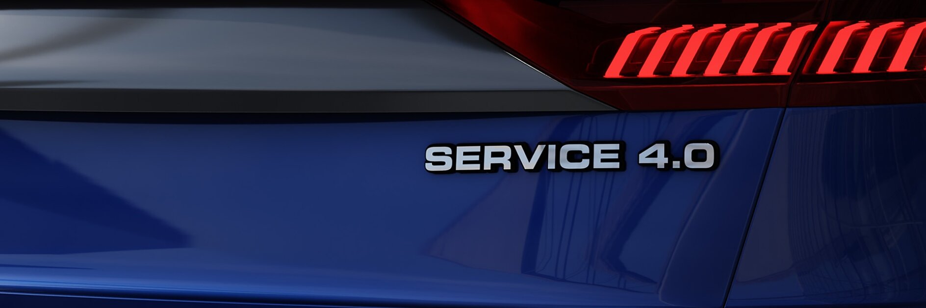The image shows the rear section of a vehicle with a smooth blue surface. A red light bar spans across the back, and the text SERVICE 4.0 is prominently displayed on the right side. The vehicles details are carefully secured using tesa tape, ensuring a sleek and seamless finish while maintaining its durability and design integrity.
