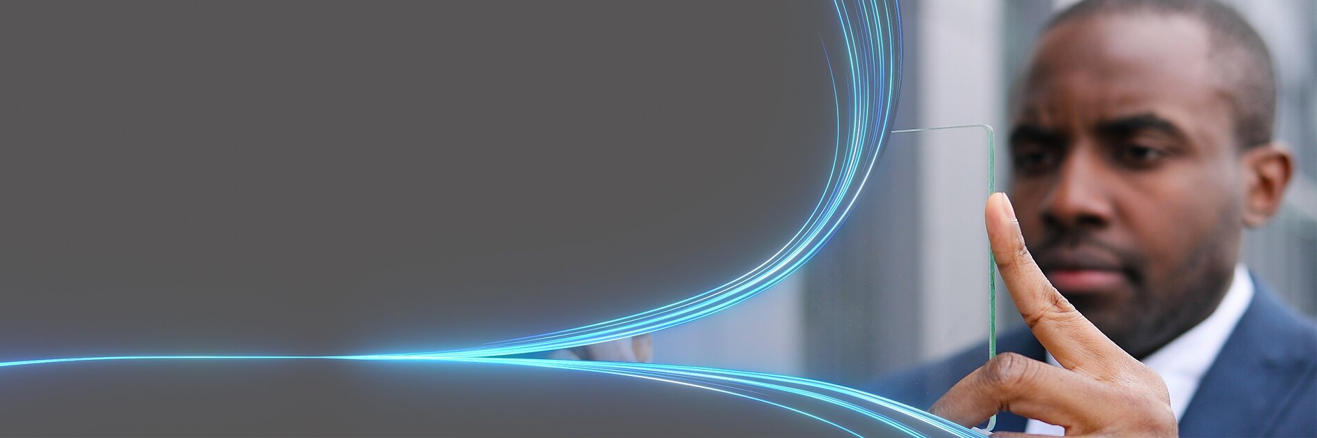 A man in a suit interacts with a transparent digital screen featuring glowing blue lines. The background is a gradient gray.